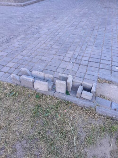 Concrete blocks stacked along the edge of a paved walkway, forming a rough curb barrier.