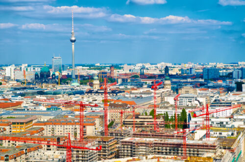 City skyline with numerous red construction cranes over a sprawling development site.