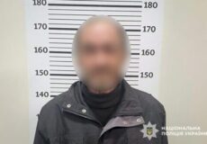 Mugshot of a man in a dark jacket with face blurred, standing before a height measurement backdrop; National Police of Ukraine watermark present.