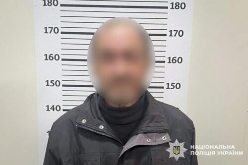 Mugshot of a man in a dark jacket with face blurred, standing before a height measurement backdrop; National Police of Ukraine watermark present.