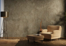 Beige armchair with matching ottoman in a modern living room corner, next to a tripod floor lamp, blue curtains, and a tall potted plant against a textured wall.