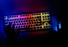 Overhead shot of a user typing on a rainbow-lit RGB keyboard with a glowing mouse in a dark room