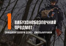 Official poster showing a bomb disposal expert in protective gear in a forest, with a large orange '1' and Ukrainian text about an explosive device.