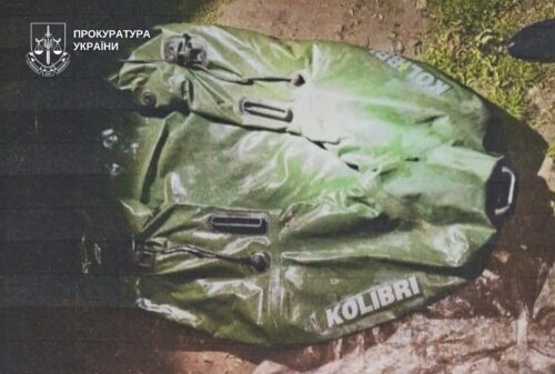 Green waterproof duffel bag with the word 'KOLIBRI' lying on dirt, top-left shows Ukrainian prosecutor's office emblem and text.
