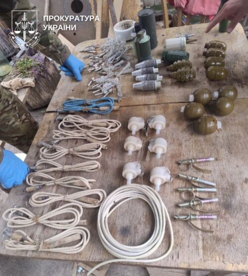 Table of seized explosive devices and military wiring: grenades, fuzes, ropes, and cords with the Ukrainian Prosecutor's Office emblem visible.