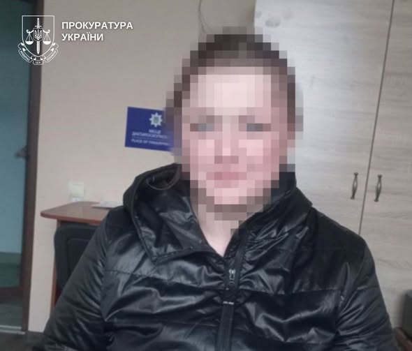 Person in a black puffer jacket seated indoors, face blurred; Ukrainian prosecutor’s office emblem visible in the top-left corner
