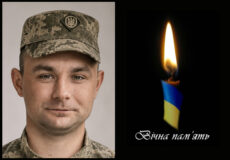 Portrait of a Ukrainian soldier in camouflage on the left and a lit blue‑yellow candle with the text 'Вічна пам'ять' on the right, signifying eternal memory/memo­rial.