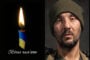 Left: lit candle with blue and yellow ribbon and Ukrainian text 'Вічна пам'ять' indicating eternal memory; Right: man wearing an olive beanie, looking at the camera with a somber expression.