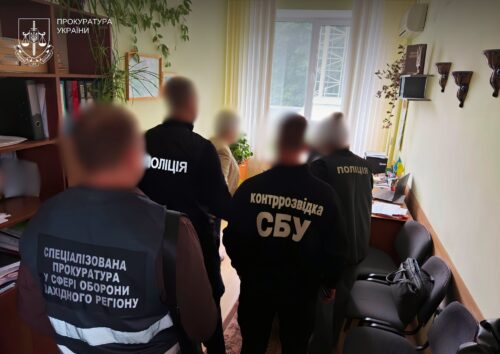 Group of officers in a Ukrainian government office wearing police and SBU counterintelligence vests, with blurred faces during a raid.
