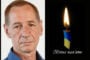 Portrait of an older man beside a lit memorial candle with a blue-yellow ribbon and the inscription 'Вічна пам'ять' (Eternal memory).