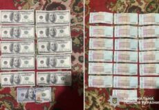Stacks of US $100 bills on the left and Ukrainian 1000-hryvnia notes on the right on a patterned rug, with a police watermark in the corner.