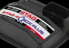 Close-up of a STAG-4 CBOX PLUS automotive control unit with a large multi-pin connector visible.