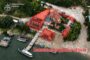 Aerial view of a riverside site with three buildings outlined in red as illegally built structures; watermark of the Ukrainian Prosecutor's Office in the corner.