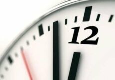 Close-up of an analog clock showing almost midnight.