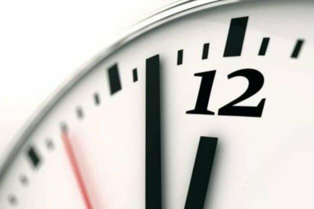 Close-up of an analog clock showing almost midnight.