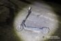 Electric scooter lying on its side on a dimly lit road at night, with the National Police of Ukraine logo in the corner.