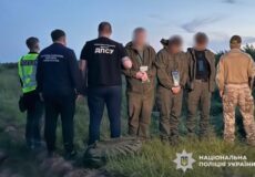 Group of uniformed officers standing in a field with blurred detainees, some in camouflage, in a police operation scene; Ukrainian National Police logo visible on the bottom right.