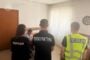 Three officers stand inside a room: a prosecutor in a black shirt reading 'ПРОКУРАТУРА' faces away, flanked by a police officer in a black 'Поліція' shirt and another officer in a bright vest marked 'Поліція'. A blurred person is present near them.