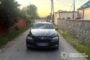 Black BMW sedan with front-end damage parked on a narrow rural street, facing the camera; police watermark bottom right.