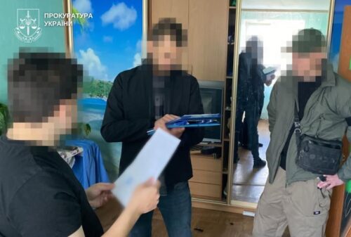 Three men indoors, one holds papers and a blue folder/tablet; Ukrainian Prosecutor's Office logo in the top-left, faces blurred.