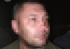 Blurry side-profile of a man wearing a green shirt and chain; Ukrainian prosecutorate watermark in the corner.