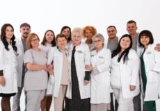 Group of doctors and nurses in white coats posing together as a healthcare team, smiling at the camera.