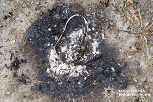 Charred debris with tangled wires on the ground, suggesting a detonated device; National Police of Ukraine watermark in the corner.