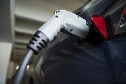 Close-up of a charging plug inserted into an electric car's charging port in a garage or station setting.