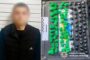 Blurred man in a dark jacket beside a police evidence tray filled with green and black drug packages.