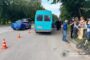 Blue minibus stopped on a road with orange traffic cones, police officers and bystanders nearby; Ukrainian police logo in corner.