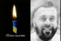 Memorial image: left candle with Ukrainian flag ribbon and 'Вічна пам’ять'; right grayscale portrait of smiling bearded man.