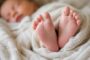 Close-up of a sleeping baby's feet wrapped in a soft blanket.