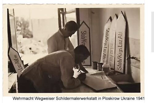Two men work at a signpost painting workshop for the Wehrmacht in Ploskirów, Ukraine, 1941, painting wooden road signs.