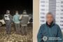 Two police officers in dark uniforms stand with a handcuffed man at night on a cobblestone surface; their backs are to the camera.