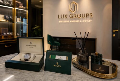 Lux Groups showroom display with an open Rolex watch box, green Rolex presentation box, and a diffuser on a marble counter near the store logo in the background.