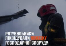 Firefighter in a red helmet beside a burned wooden outbuilding; overlaid headline: 'Рятувальники ліквідували пожежу господарчої споруди'.