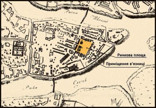 Historic map of a town showing a prison complex; a yellow-highlighted building near the market square and prison premises along a river.