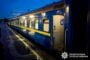 Blue passenger train car at a wet platform at dusk, door open on the side.