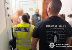 Shirtless man with a blurred face surrounded by police in a hallway; one officer wears a 'CRIMINAL POLICE' shirt.
