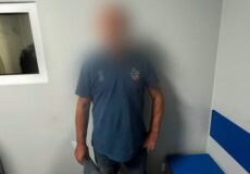 Blurry photo of a man in a blue T-shirt standing in a small room with pale walls and blue benches; Ukrainian police watermark in the bottom right.