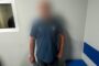 Blurry photo of a man in a blue T-shirt standing in a small room with pale walls and blue benches; Ukrainian police watermark in the bottom right.