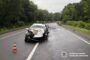 White sedan badly damaged in a road collision on a wet highway, orange traffic cone in front; National Police of Ukraine watermark in corner.