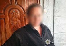 Blurry image of a man in a dark jacket standing by a carved wooden door; police watermark visible in the bottom-right corner.