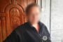 Blurry image of a man in a dark jacket standing by a carved wooden door; police watermark visible in the bottom-right corner.