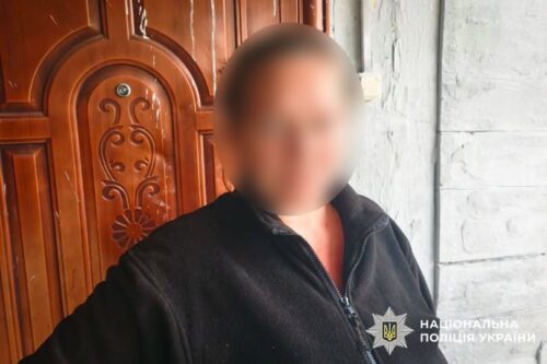 Blurry image of a man in a dark jacket standing by a carved wooden door; police watermark visible in the bottom-right corner.