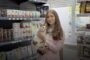 Woman holding a cat in a pet store, smiling, with product shelves behind and logos above, Ukrainian caption about an employment service project.